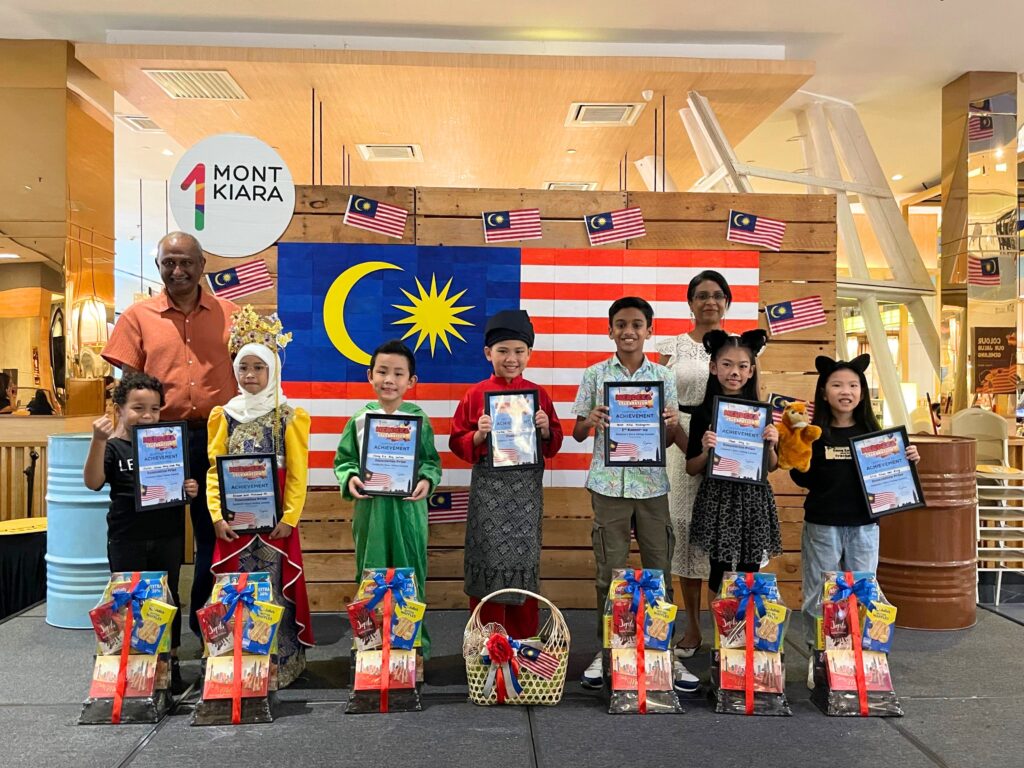 Winners of the 1 Mont Kiara Merdeka Children Storytelling Contest flanked by judges Mr. Thiru and Ms. Malar. (From L-R): Xavier Chisom Ming Umeh Ang, Ahlaam binti Mohamad Ali, Chong Ka Seng Carlson, Karlson Tan Thien An, Varun Pillai Prabagaran, Cheah Xing En, and Elsa Khaw Wen Qing.